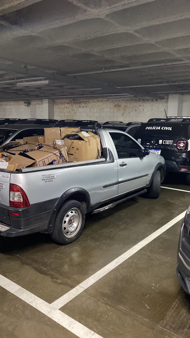 Caçamba da Strada cheia de caixas de papelão presas com corda, num estacionamento coberto